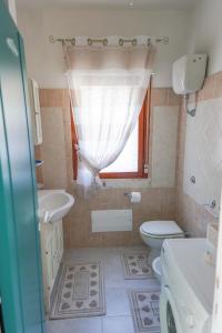 baño con lavabo y aseo y ventana en Casa Ilaria Calaliberotto, en Cala Liberotto