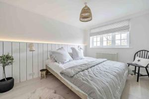 a white bedroom with a bed and a chair at sea side cottage near beach in West Wittering