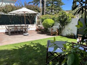 un patio con mesa, sillas y sombrilla en See You Again Caparica, en Costa da Caparica