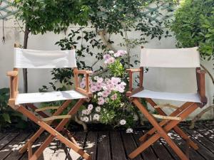 dwa krzesła siedzące obok siebie przed kwiatami w obiekcie See You Again Caparica w Costa de Caparica