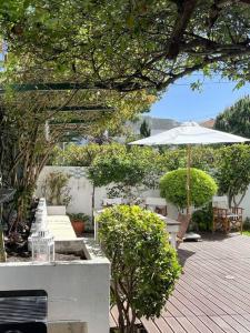 un patio con sombrilla, mesa y sillas en See You Again Caparica, en Costa da Caparica