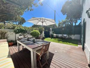 a wooden deck with a table and an umbrella at See You Again Caparica in Costa da Caparica