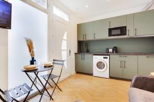 une cuisine avec un lave-linge et une table avec des chaises dans l'établissement CMG - Modern apartment 4P- Levallois Anatole France, à Levallois-Perret