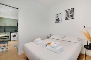 - une chambre blanche avec un lit et des serviettes dans l'établissement CMG - Modern apartment 4P- Levallois Anatole France, à Levallois-Perret