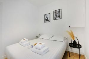 - une chambre avec un lit blanc et des serviettes dans l'établissement CMG - Modern apartment 4P- Levallois Anatole France, à Levallois-Perret