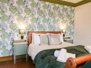 a bedroom with a bed with green and white wallpaper at The Old Post Office in Matlock