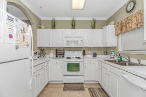 a kitchen with white cabinets and a white refrigerator at Barefoot In The Sun at Barefoot Resort & Golf in North Myrtle Beach