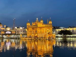 a lit up golden temple with water in front of it at Homestay Comforts 500m from Amritsar Airport in Amritsar