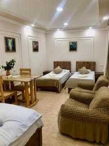 a room with two beds and a table and chairs at Guest House Anahit Ijevan in Ijevan