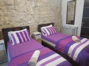 two beds in a room with purple and white at אורות בעתיקה - צימרים ונופש בצפת in Safed