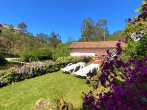 a group of white chairs in a garden with flowers at Casa da Azenha Branca in Castelo do Neiva