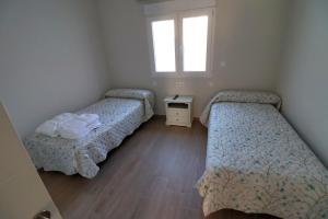 een kamer met 3 bedden en een raam bij APARTAMENTOS MESTRE in Ayamonte