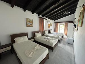 um quarto com três camas e uma televisão em Ara E Vjeter Resort em Velipojë