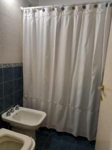 La salle de bains est pourvue d'un rideau de douche blanc et de toilettes. dans l'établissement Casa de campo El Zoki, à Villa Anizacate