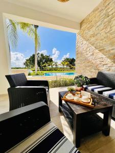 sala de estar con sillas, mesa y piscina en Relax Apto Pool and Golf View in Hard Rock Golf en Punta Cana
