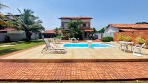 une terrasse avec des chaises et une piscine dans la cour. dans l'établissement Village Itaúna Inn, à Saquarema