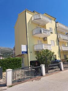 a yellow building with balconies on the side of it at Apartments Nena in Podstrana