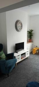 sala de estar con TV, sofá y reloj en Rydal house with office space newly refurbished en Newton-le-Willows