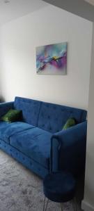 un sofá azul en una sala de estar con una pintura en Rydal house with office space newly refurbished en Newton-le-Willows
