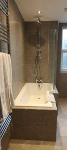 a bathroom with a bath tub with a shower at Rydal house with office space newly refurbished in Newton-le-Willows