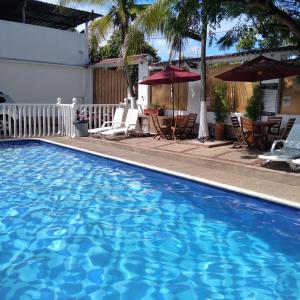 uma piscina num hotel com cadeiras e guarda-sóis em HOTEL MACEO MELGAR em Melgar