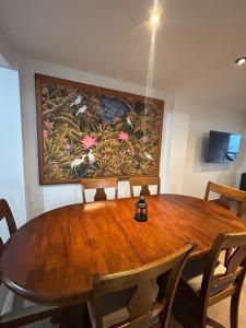 una mesa de madera con sillas y una pintura en la pared en Apartamento Huanchaco Yuri en Huanchaco