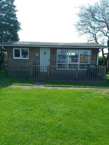 a small house with a porch and a yard at No 27 A dog friendly rural coastal chalet in Seaton