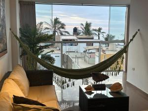 a hammock in a living room with a large window at Apartamento Huanchaco Yuri in Huanchaco