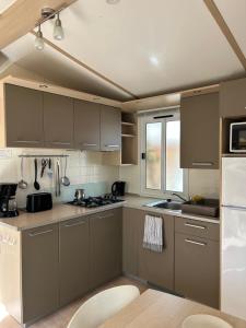 a kitchen with gray cabinets and a white refrigerator at Les mobil homes de Naka , camping le NOVELA in Port-la-Nouvelle