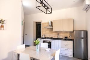 a kitchen with a table and a stainless steel refrigerator at Atrepassidalmare in Marina di Ragusa +2 photos