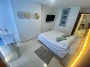 a white bedroom with a bed and a mirror at Hermoso apartaestudio con jacuzzi en zona social in Bucaramanga