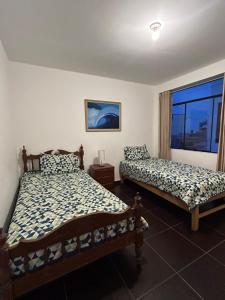 two beds in a room with a window at Lindo apartamento en Huanchaco, con vista al mar in Huanchaco