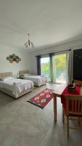 a bedroom with two beds and a table and a window at Kaş Merkezde Konforlu Apart-2 The Rush-2 in Kas