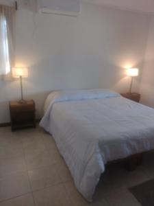 a bedroom with a white bed and two lamps at Las Marukas in San Antonio de Areco