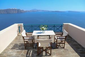 een tafel en stoelen op een balkon met uitzicht op het water bij Oia VineyART Homes in Oia