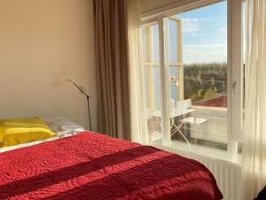a bedroom with a bed and a window with a view at Amstel BeachHouse Egmond aan Zee, 50m from the beach! in Egmond aan Zee