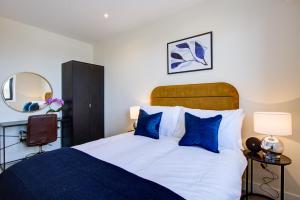a bedroom with a bed with blue pillows and a mirror at Hybrid Resi - London, Sutton, FREE on-site Car or Van parking in Cheam