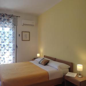een slaapkamer met een bed met 2 lampen en een raam bij Piccolo Hotel Nuova gestione in Cala Gonone