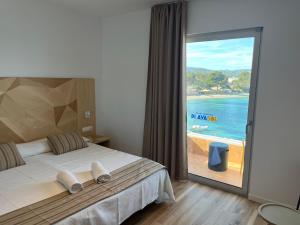 a bedroom with a bed and a view of the ocean at Apartamentos Playa Sol in Es Cana