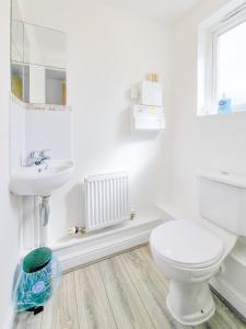 a white bathroom with a toilet and a sink at Milton Keynes 5BR Contractor house, families/ groups welcome. in Broughton