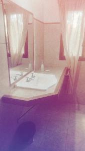 uma casa de banho com uma banheira e um espelho grande em Las Marukas em San Antonio de Areco