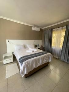 a bedroom with a large bed and a window at LEGENDS EXECUTIVE LODGE in Choma