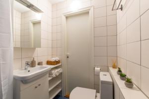a white bathroom with a sink and a toilet at Stylish Central Apartment by Kuus Sõlme in Kuressaare