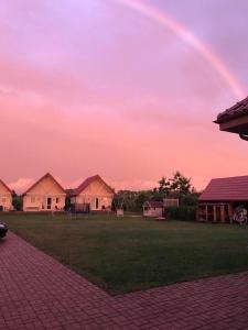 a rainbow in the sky over a yard with houses at Pokoje gościnne u Izy in Łeba
