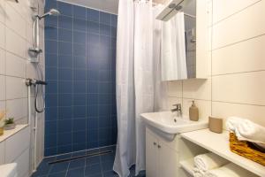a blue tiled bathroom with a shower and a sink at Stylish Central Apartment by Kuus Sõlme in Kuressaare
