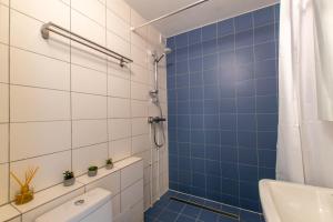 a blue tiled bathroom with a shower and a toilet at Stylish Central Apartment by Kuus Sõlme in Kuressaare