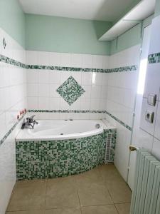 e bagno con vasca decorata con piastrelle verdi e bianche. di Maison et Piscine à 10min d’Aix/20min de Marseille a Bouc-Bel-Air