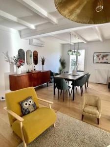 ein Wohnzimmer mit einem gelben Stuhl und ein Esszimmer in der Unterkunft Maison et Piscine à 10min d’Aix/20min de Marseille in Bouc-Bel-Air