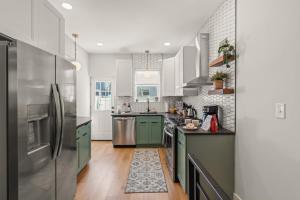 a kitchen with green cabinets and a stainless steel refrigerator at Family Fun South Philly Game House Near Sports Stadiums and Concerts in Philadelphia