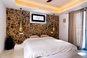 um quarto com uma cama e uma parede de pedra em Cortijo Almarchal em El Almarchal